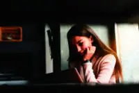 Depressed female teen in a dark room reading